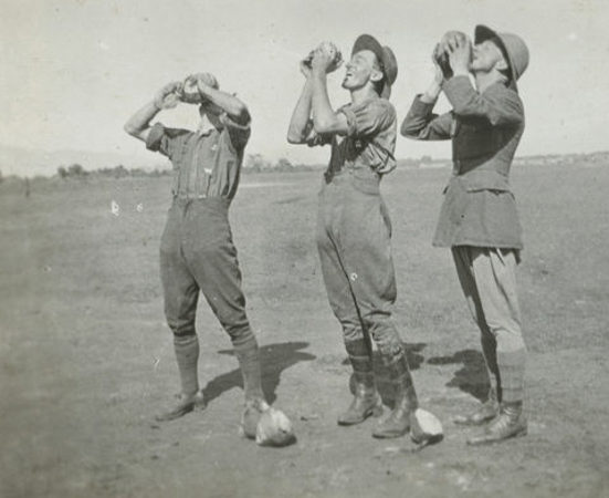 Three men standing drinking water