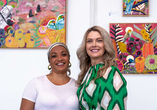 Two female artists standing in front of their artworks at Adelaide Airport.