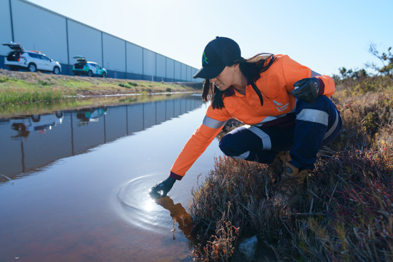 woman in high vis touches creek water