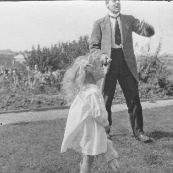 A man and a young girl in a garden looking up at something
