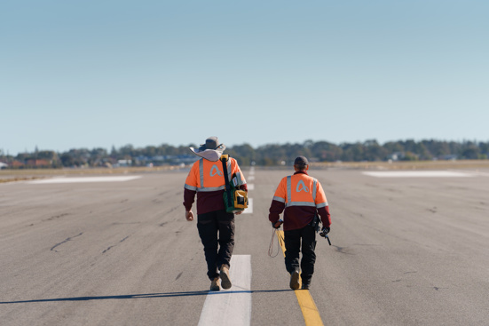 2 people in adelaide airport hi vis walk along the runway