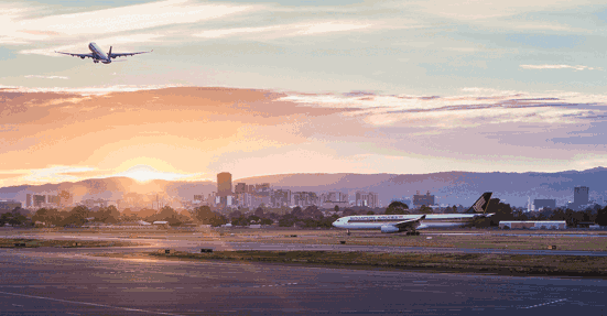 Plane taking off over sunrise and city skyline 