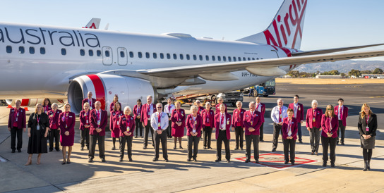 Ambassadors taking a group photo on the Tarmac with plane in the background 
